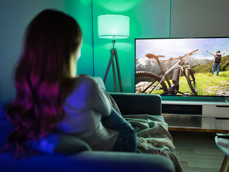 Frau auf der Couch in ihrem Smart Home vor dem TV Frau auf der Couch in ihrem Smart Home vor dem TV